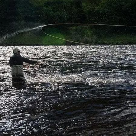 Angler with a single handed fly rod fighting a fish