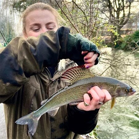 Lady in the stream with her fabulous grayling catch