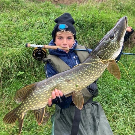Young angler with a fantastic pike catch with the fly tackle on their back