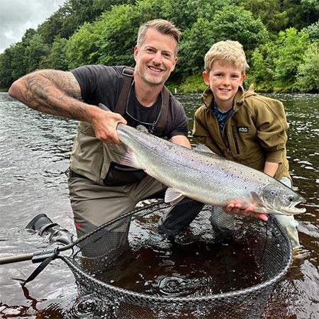 James Stockoe with young angler in the middle of the river with his first salmon catch