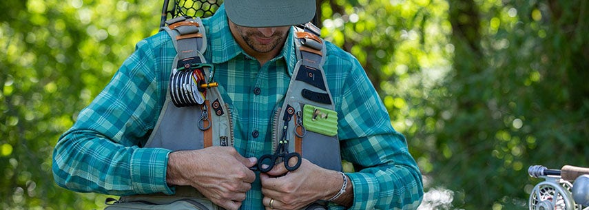 Fishing Vests & Waistcoats Man doing up a fly fishing vest loaded with accessories