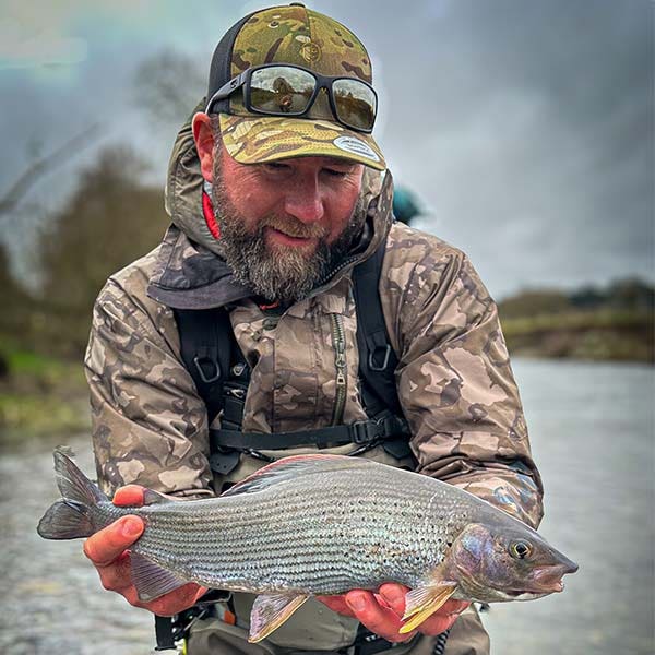 Chris holding a stunning grayling whilst wading in the river